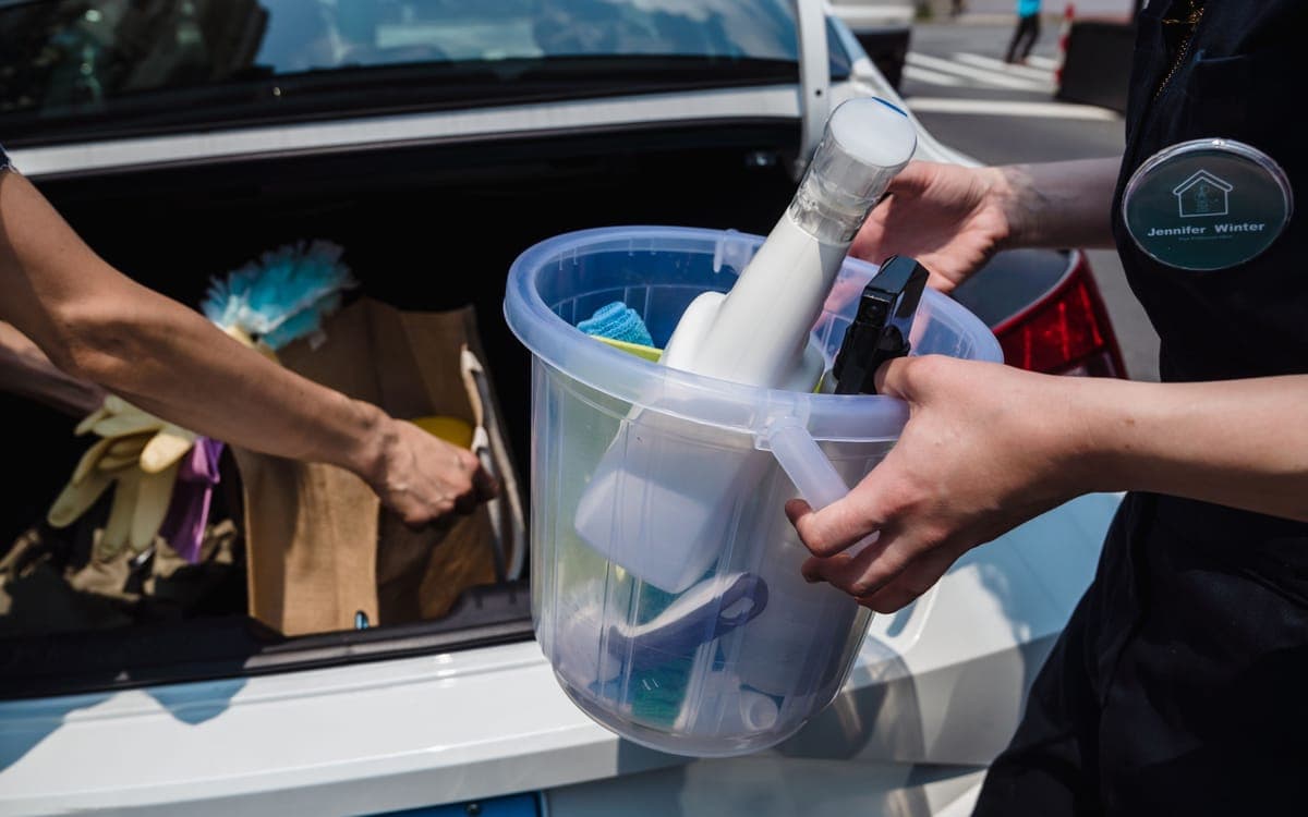 A detailing bucket kit with bottles and towels arranged on a driveway