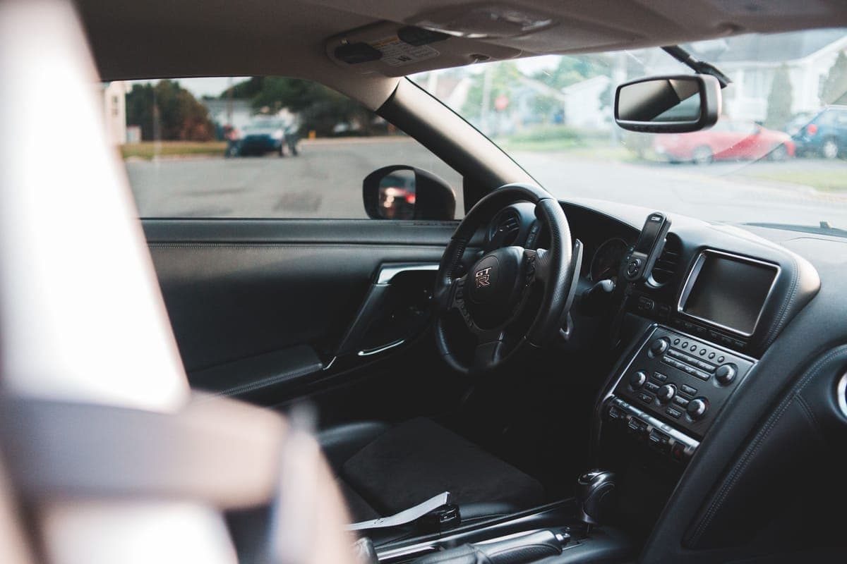 A cleaning cloth and spray bottle on a clean car dashboard in daylight