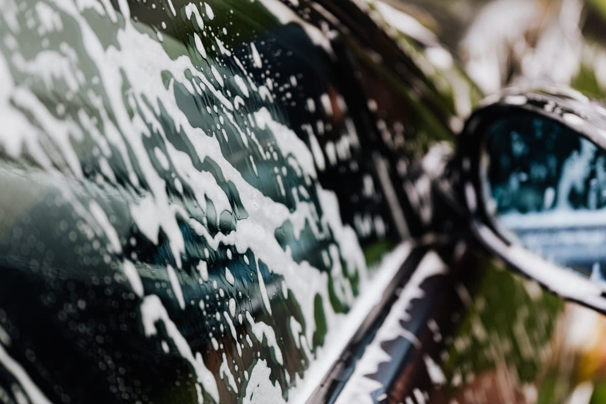 Thick soap suds on the hood of a glossy coated car
