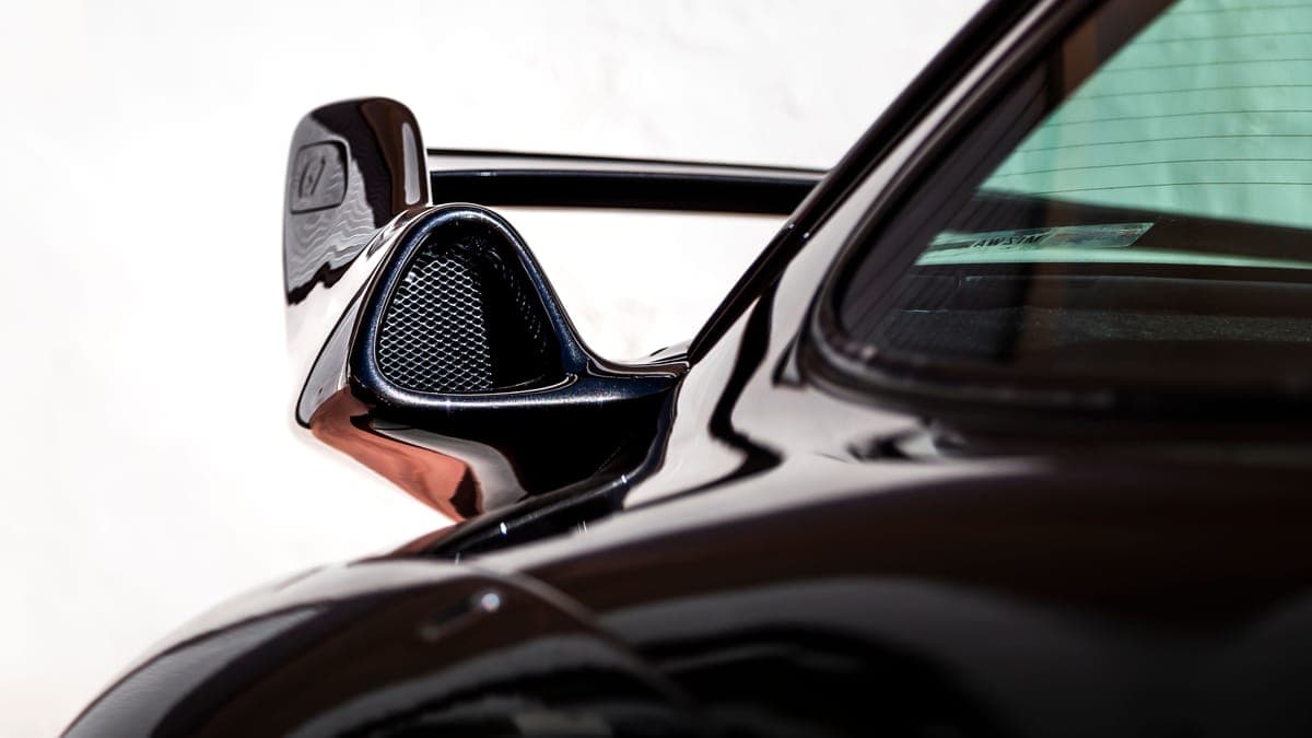 Sunlight reflecting off the curved rear fender of a dark colored car