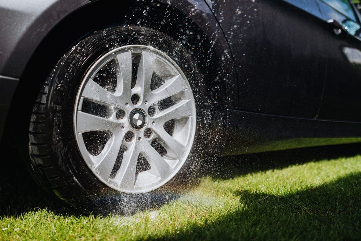 A clean multi-spoke alloy wheel photographed in bright daylight against pale paint