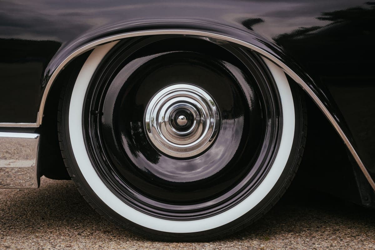 A whitewall tire on a glossy black wheel