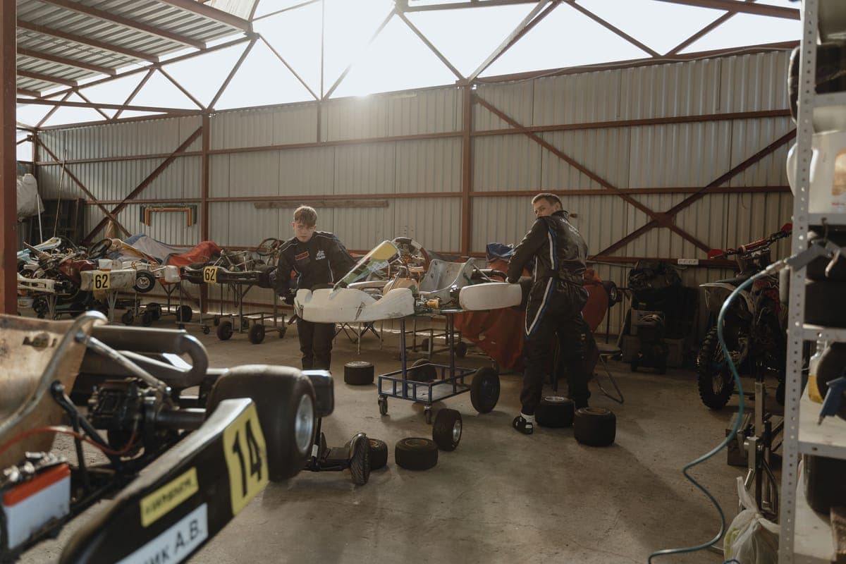 A rolling cart of detailing bottles beside a car in a garage