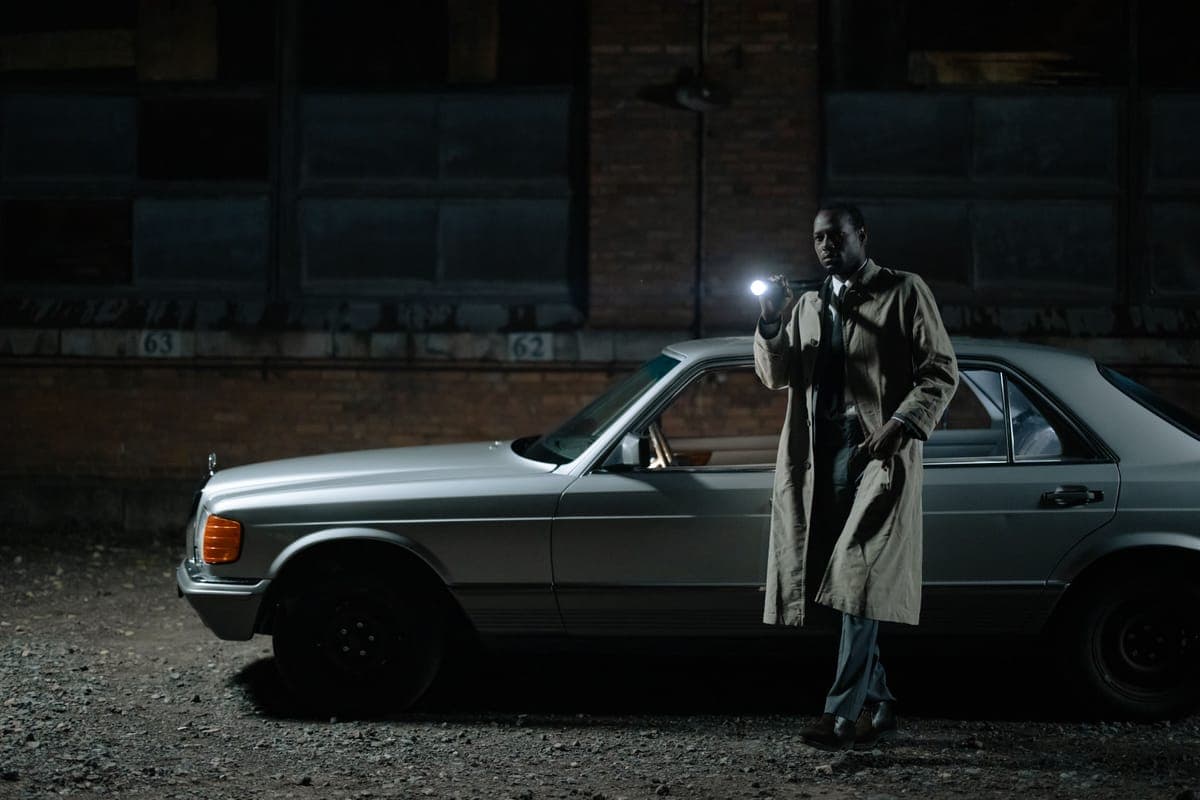 A handheld LED light held close to a dark car panel