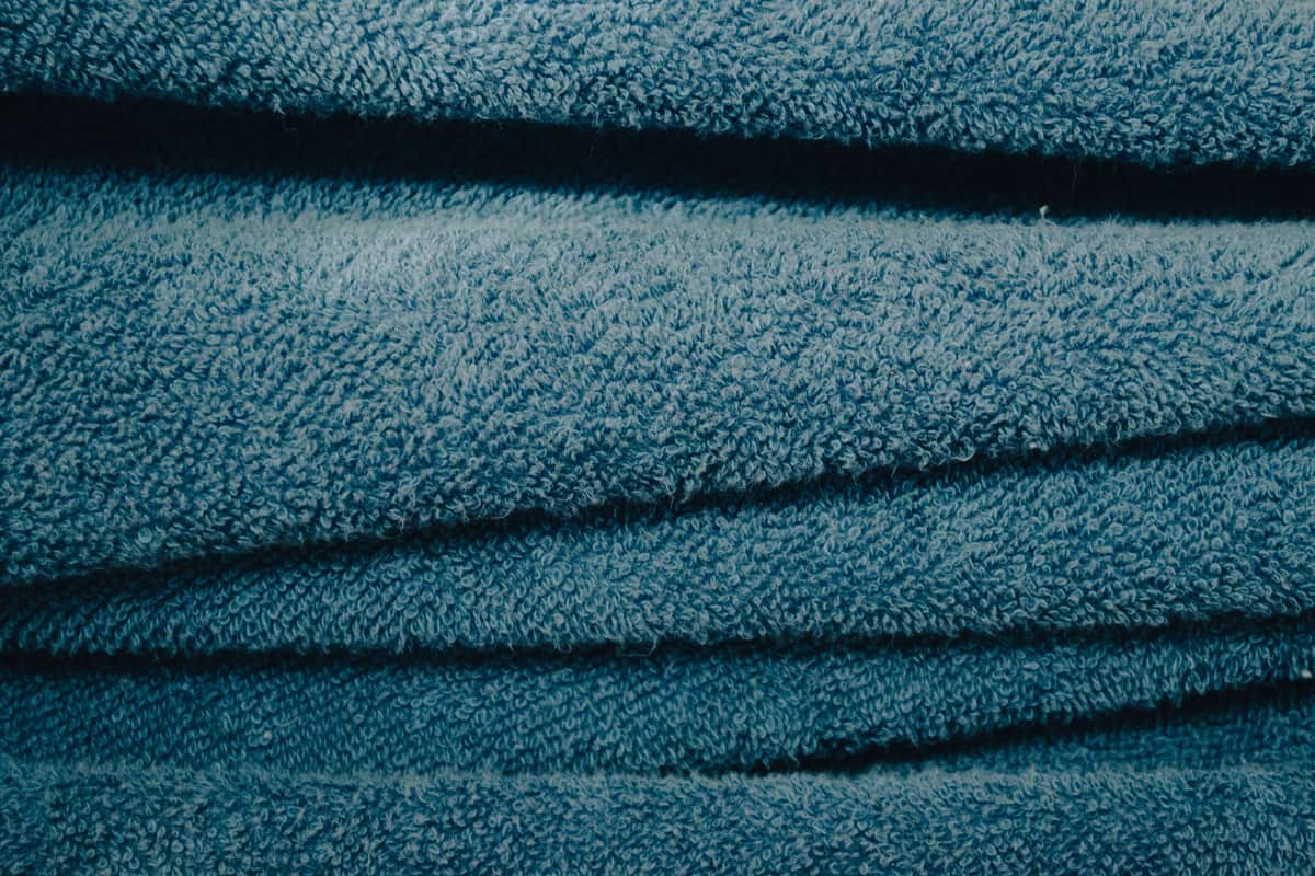 A plush drying towel laid flat across the wet hood of a car
