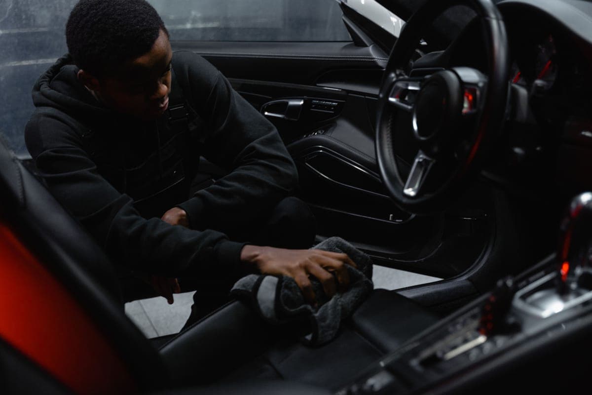 A leather car seat being wiped with a soft cloth and foam cleaner