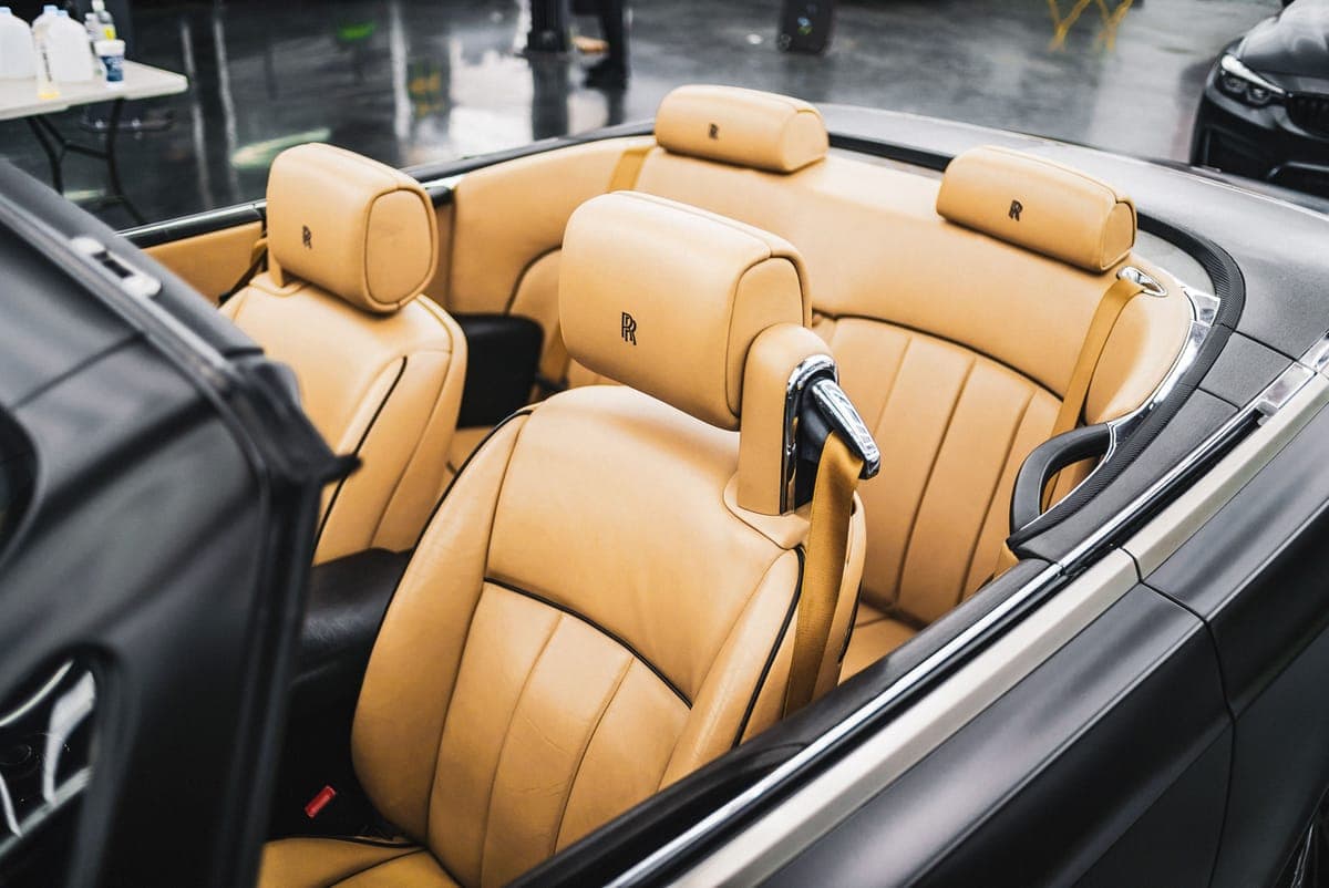 A soft cloth applying conditioner to a tan leather car seat