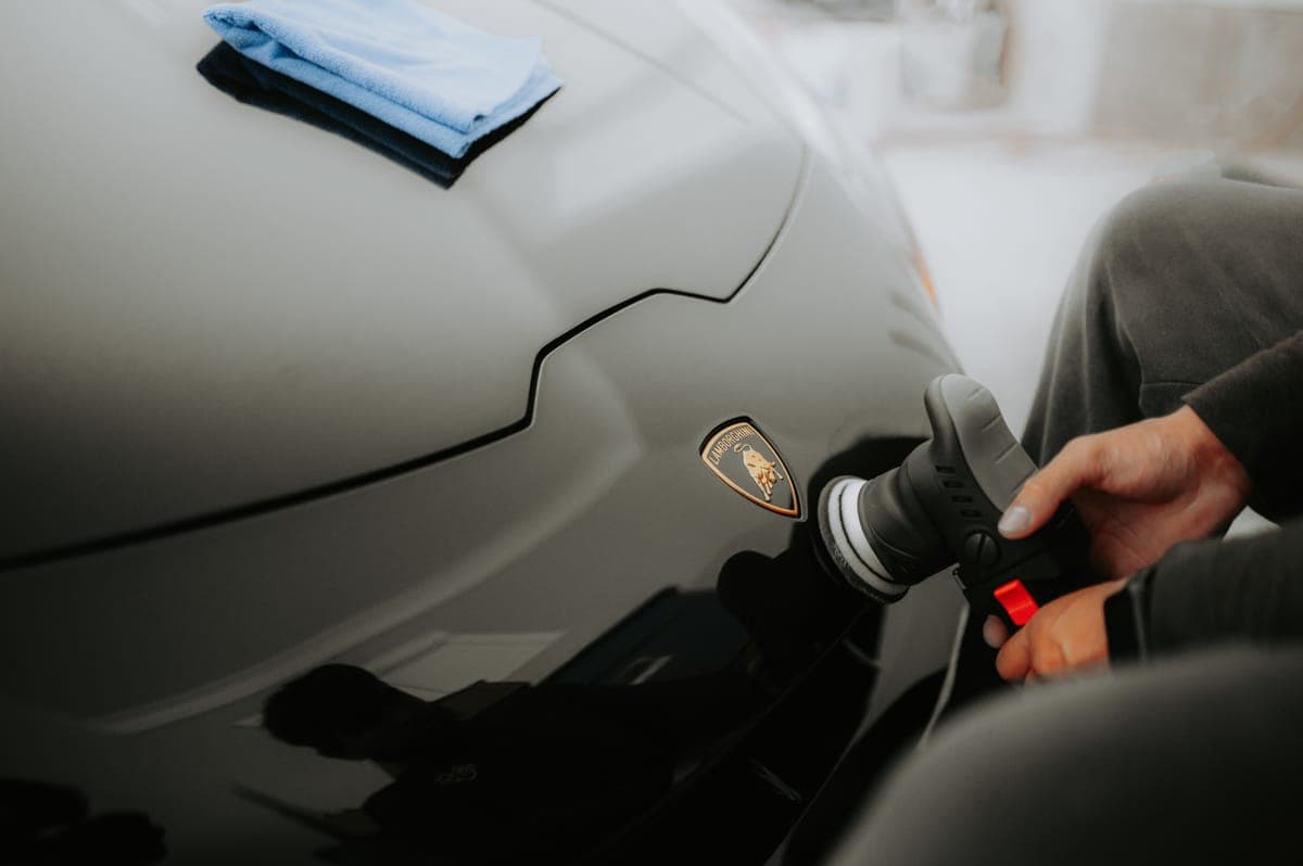 A microfiber towel wiping a pale blue car door panel to a high gloss