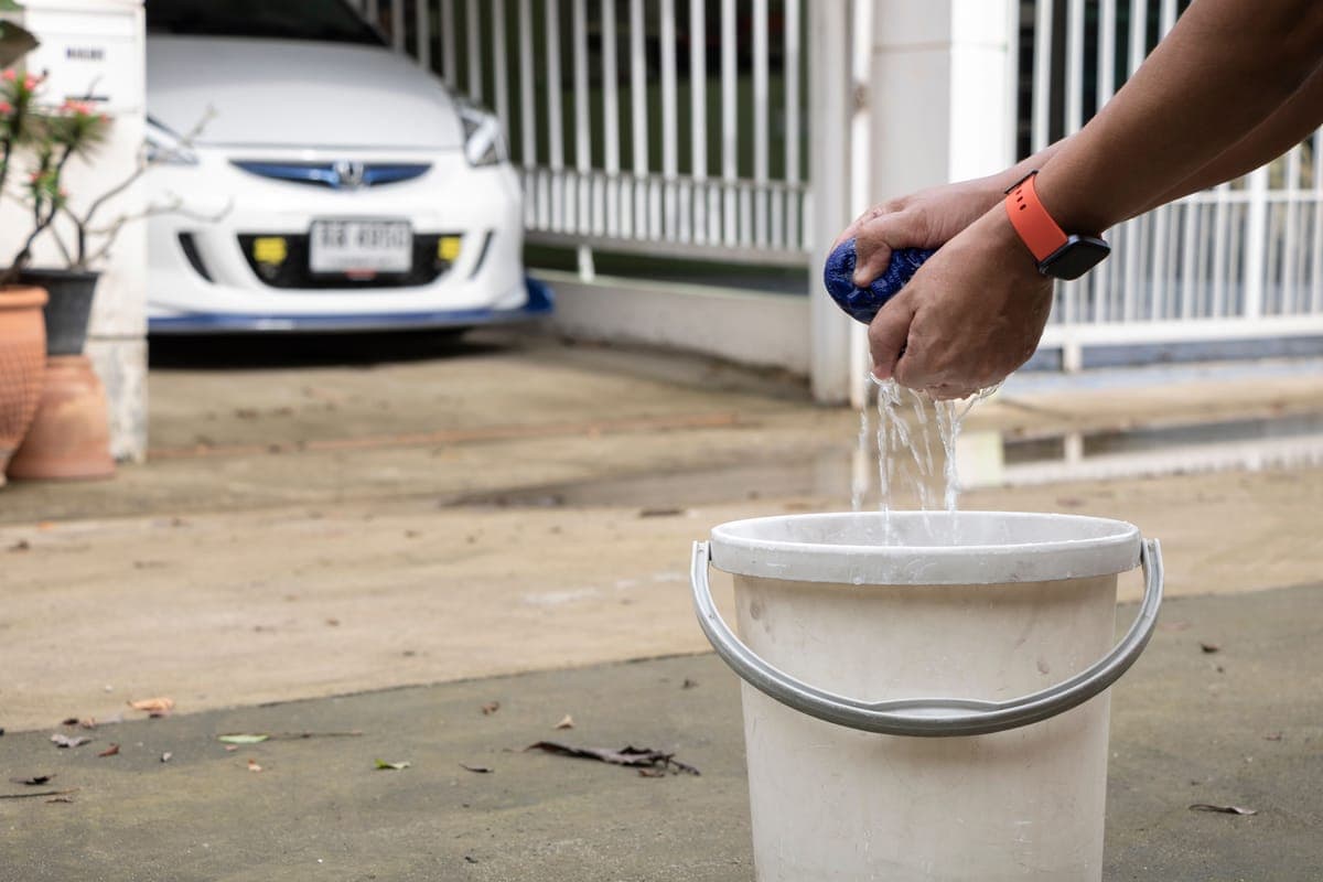 Two wash buckets with grit guards and a wash mitt on a driveway