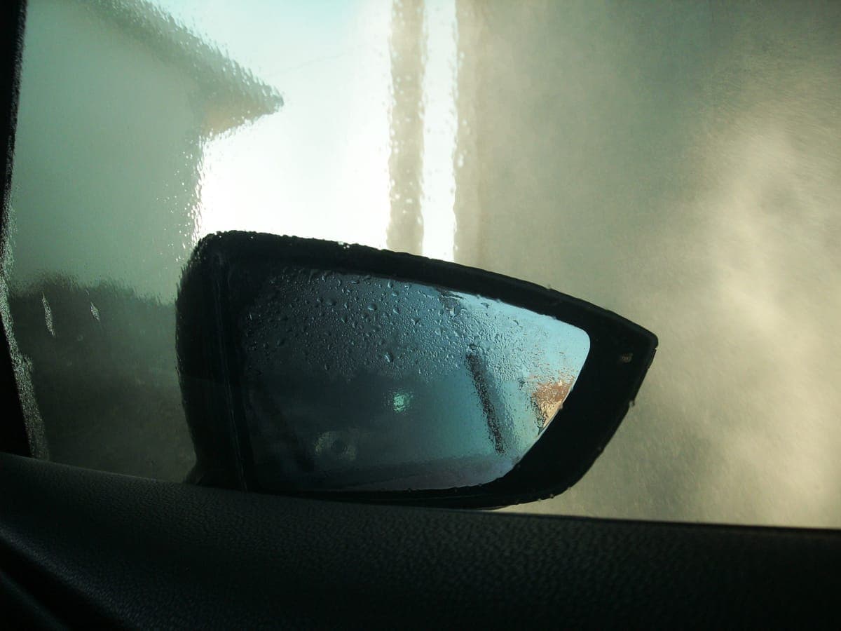Dried water spots visible across a dark car body panel in daylight