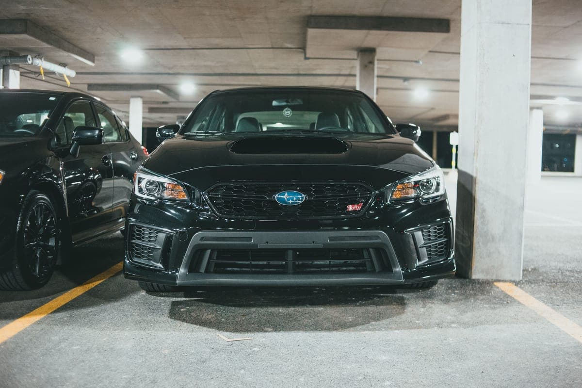 A black car parked inside a concrete parking garage