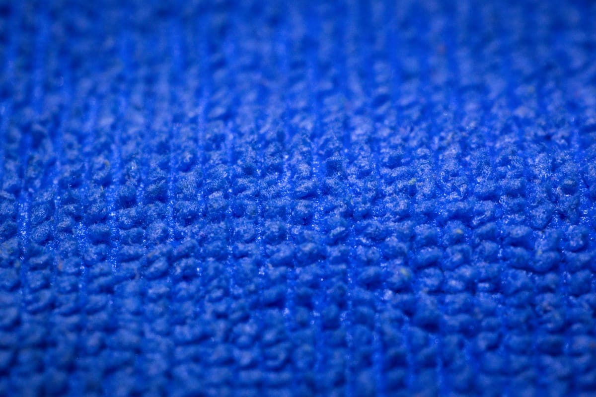 A folded plush drying towel resting on the roof of a wet car