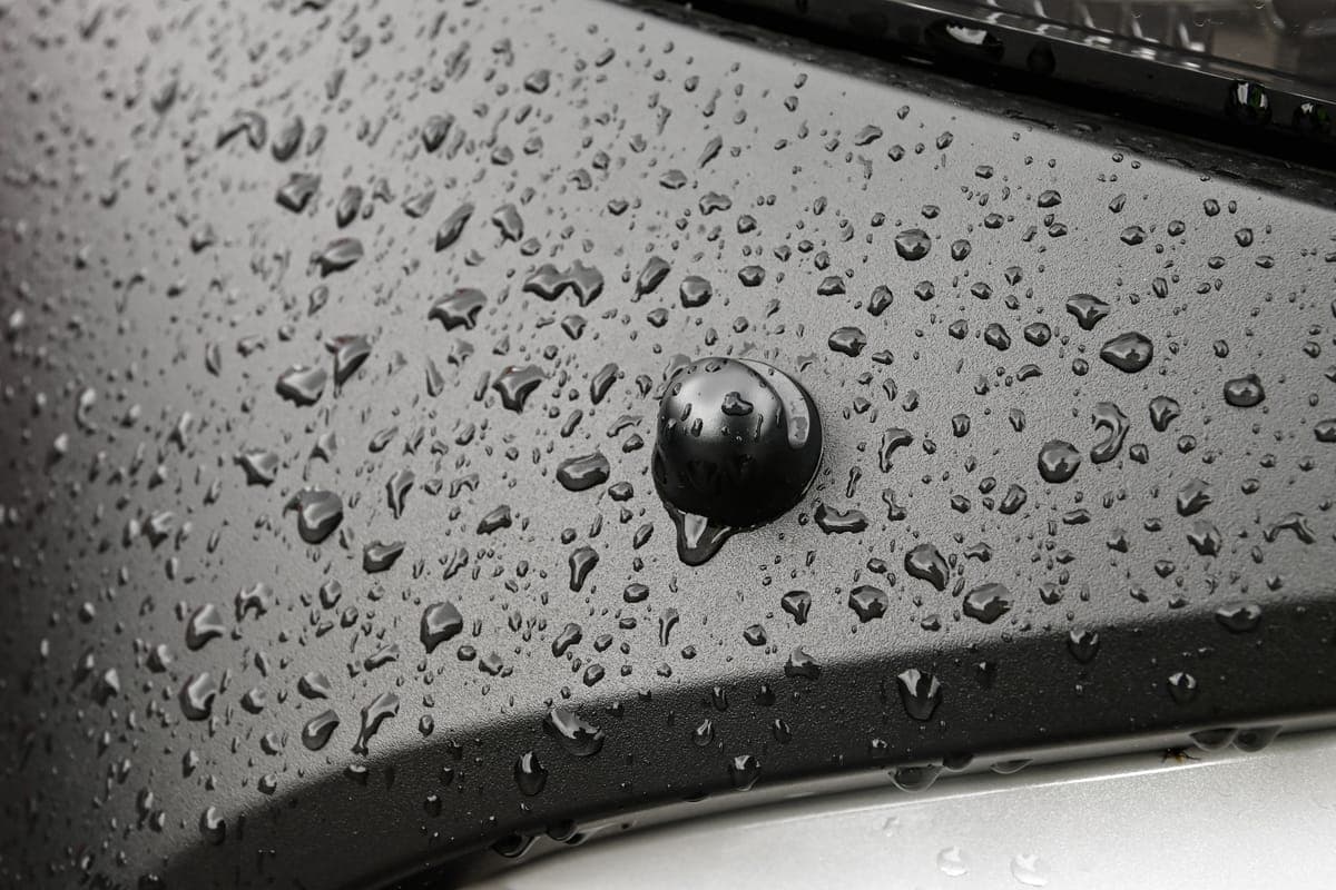 Close view of water droplets on a dark coated body panel