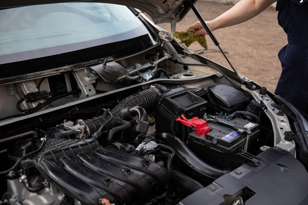 An open hood over an engine bay, with a cloth held at the edge of the frame