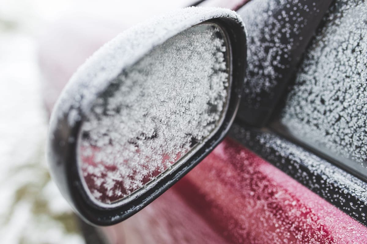 Frost covering the wing mirror and side window of a red car