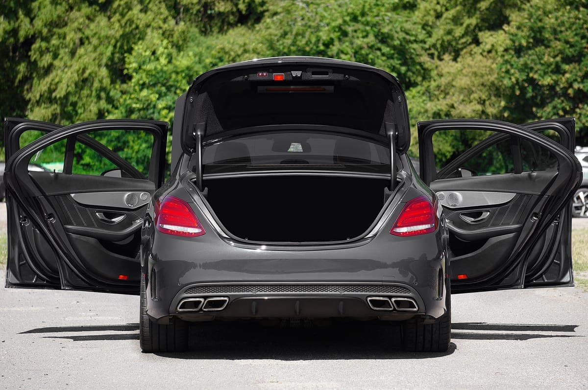 A car with its doors open airing out in bright daylight