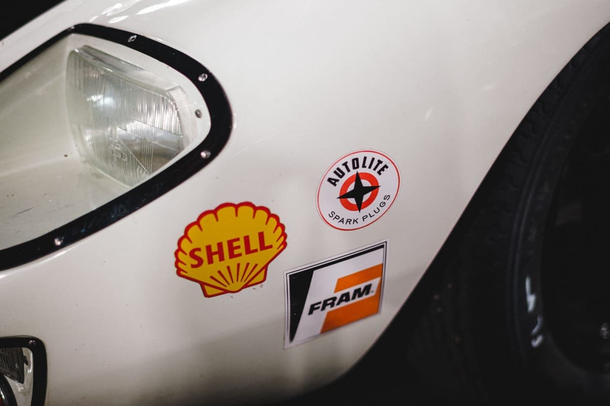 Sponsor decals stuck to the white front fender of a car