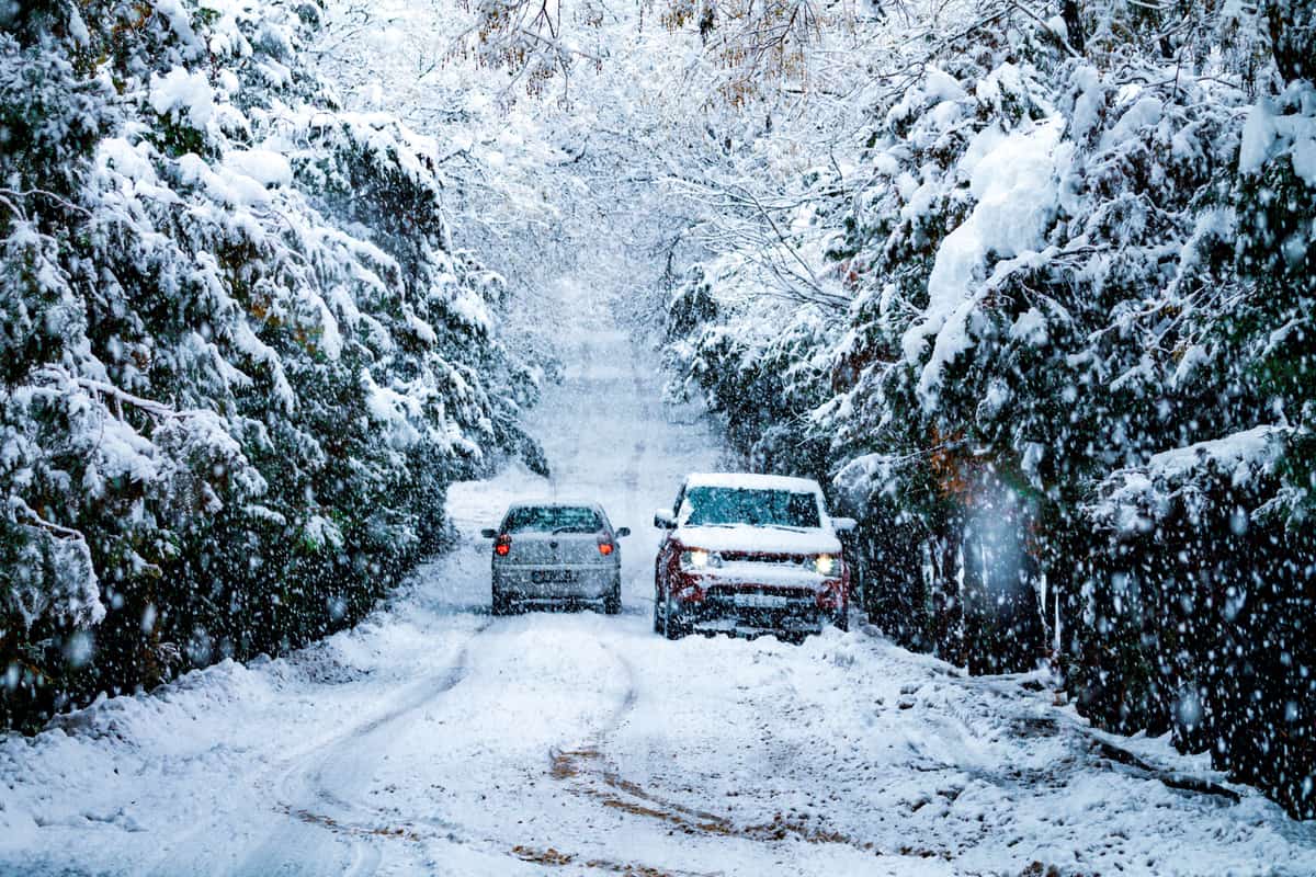 Two cars on a snow-covered road during a snowfall