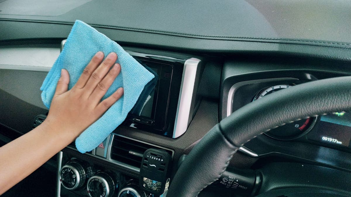 A tidy car interior mid-clean with brushes and towels on the seat