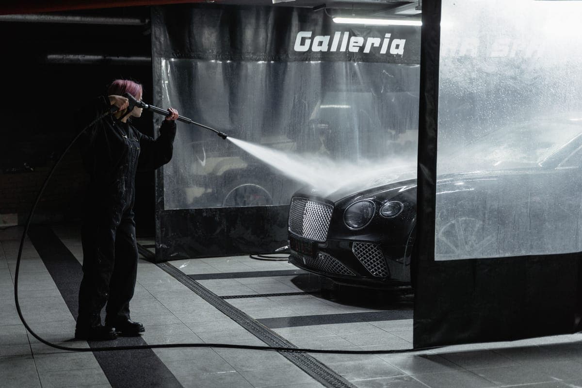 A pressure washer rinsing foam off a car