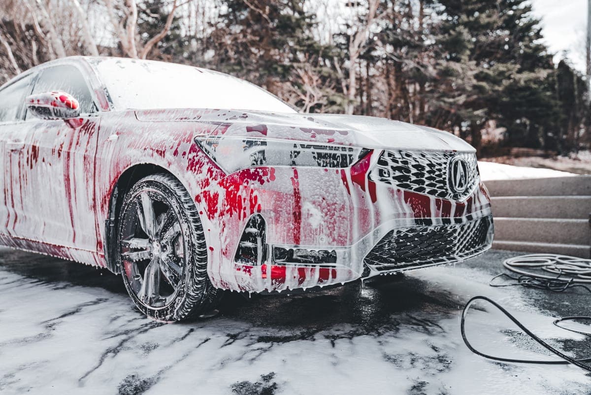A car covered in thick white foam after a pre-wash