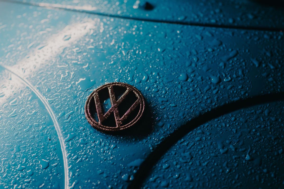 Water beaded across a blue car hood around a badge
