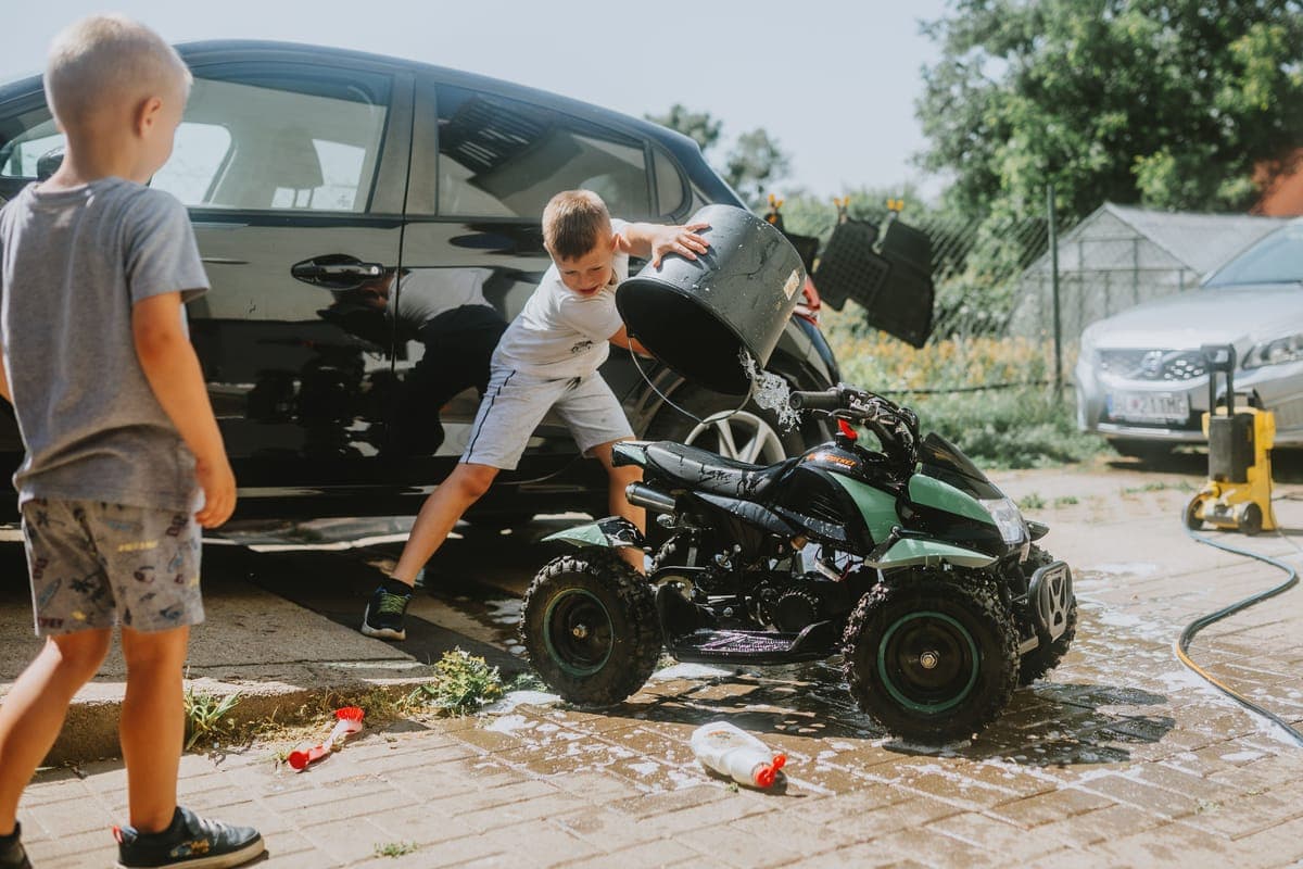 A wash bucket full of suds beside a car