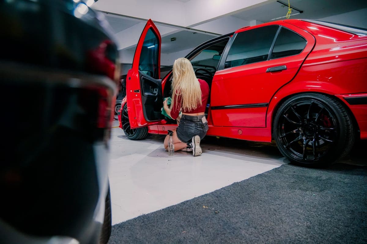 Someone cleaning the interior of a red car with the door open