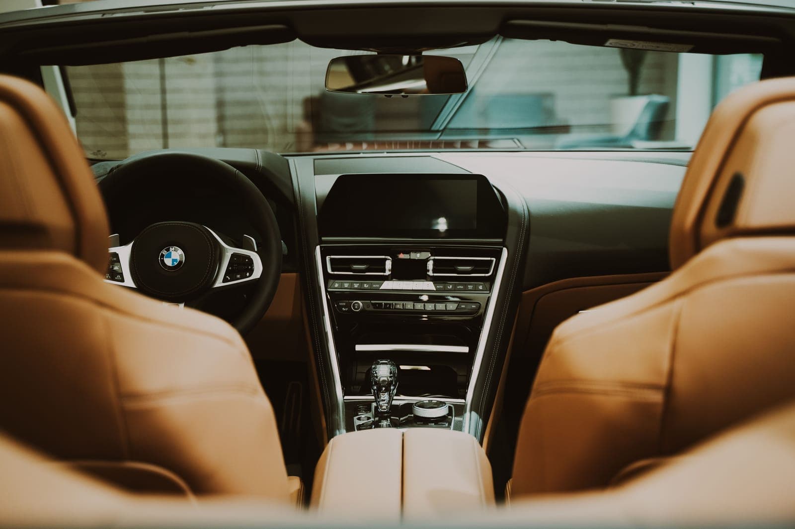 Clean tan leather car seats and dashboard lit by soft daylight through the windshield